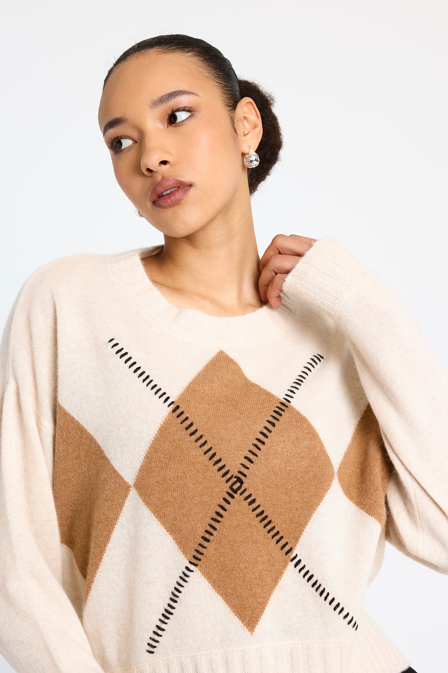 cream round neck cashmere jumper with rib detailing and tan argyle design on the front model shot