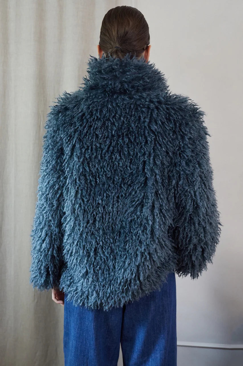 Blue faux fur short jacket worn with blue jeans rear view