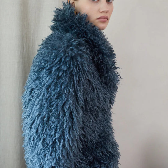 Blue faux fur short jacket worn with blue jeans side view close up
