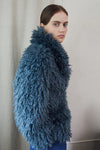 Blue faux fur short jacket worn with blue jeans side view close up