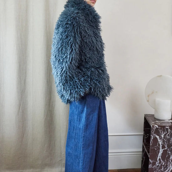 Blue faux fur short jacket worn with blue jeans side view