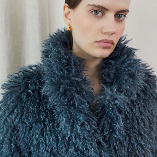Blue faux fur short jacket worn with blue jeans close up of neck