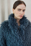 Blue faux fur short jacket worn with blue jeans close up of neck