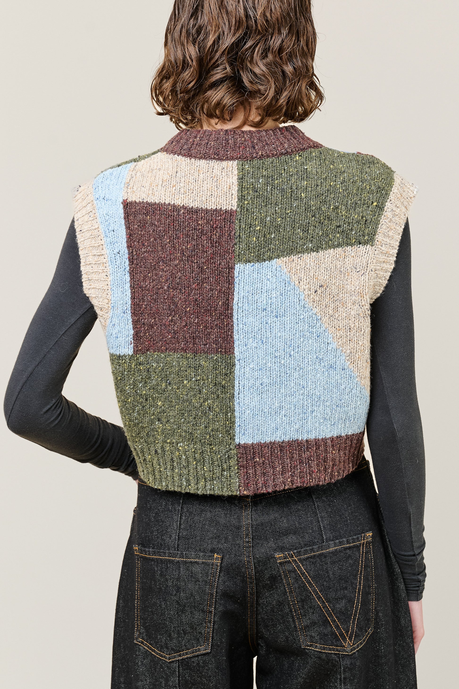 woman wearing multi colour geometric knit vest rear view