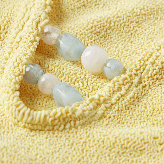 Close up detail of blue bead detail on one size yellow swimsuit from Hunza G