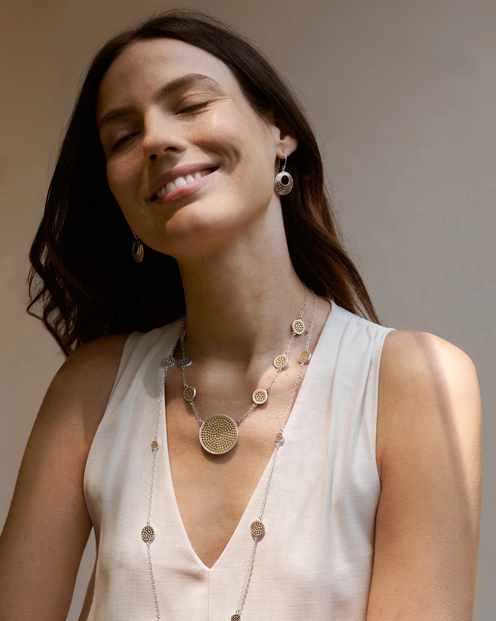 Long silver station necklace with alternating small and medium silver discs with gold dot details