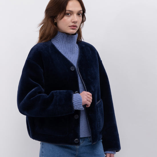 navy faux fur reversible round neck jacket with patch pockets, long sleeves, black buttons and interior dark navy faux suede with fur detailing model shot