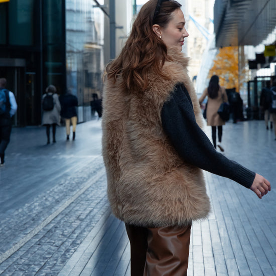 longer faux fur reversible gilet with 3 gold buckles on the front, slit pockets and interior faux suede model shot