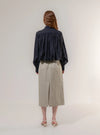 Person wearing a navy shirt and beige skirt on a white background