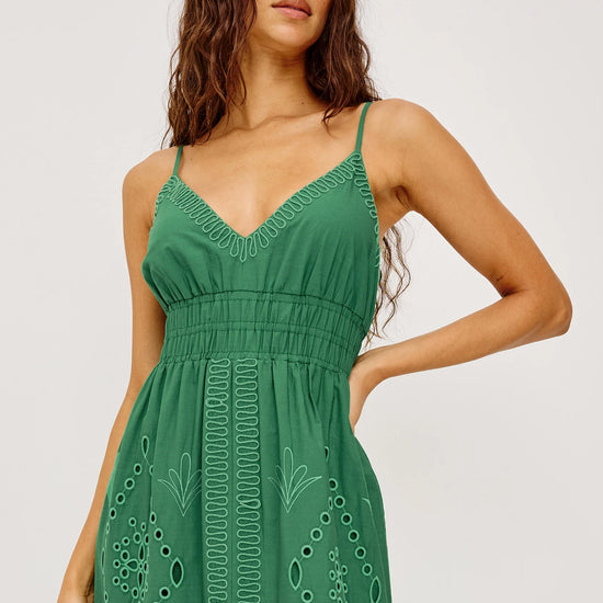 Woman wearing a green dress with floral patterns on a white background