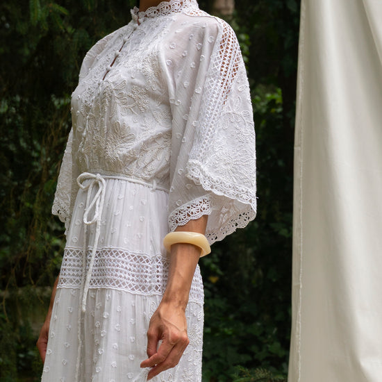 White lace dress worn by a person with a blurred background