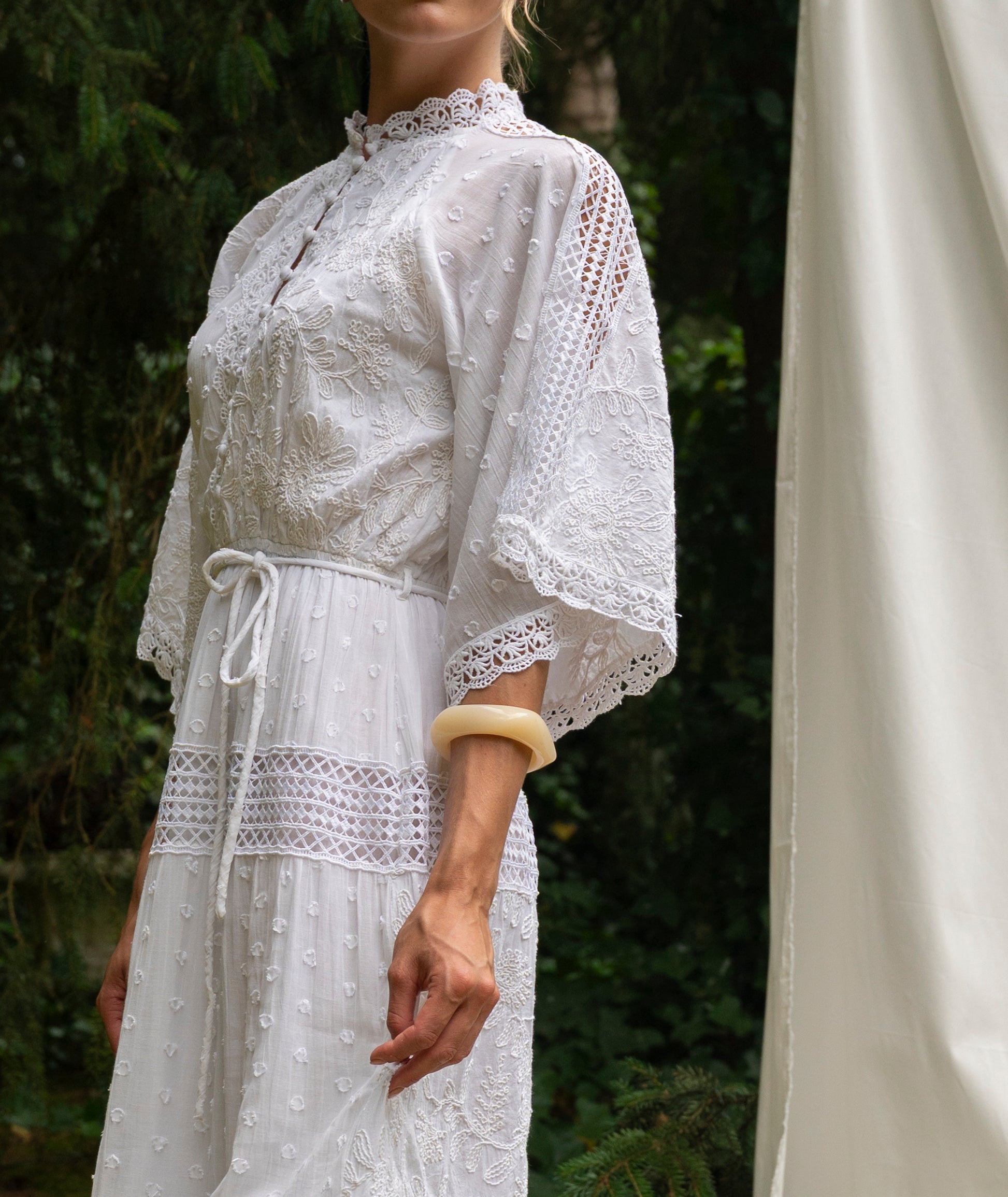 White lace dress worn by a person with a blurred background