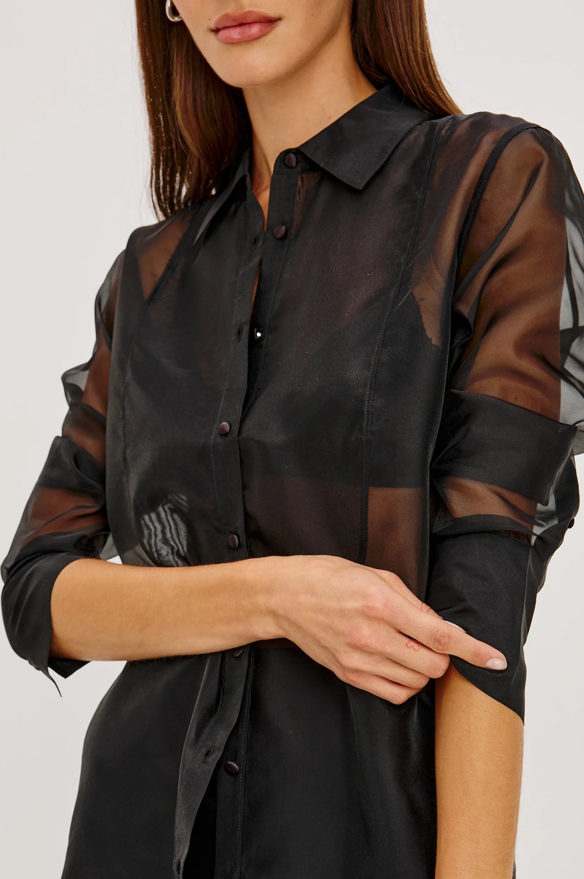 close up of a Model wearing a sheer black button up shirt with a black slip skirt 