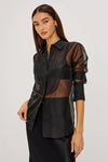 Model wearing a sheer black button up shirt with a black slip skirt 
