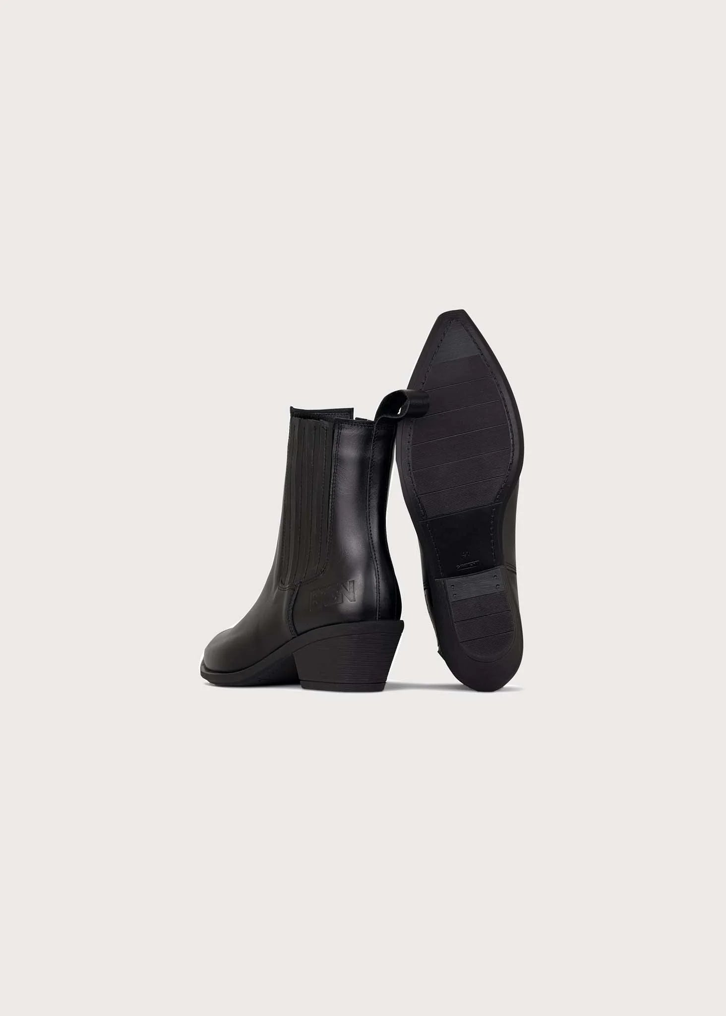A pair of black leather ankle boots with low block heels, shown from the side and sole views against a light gray background.