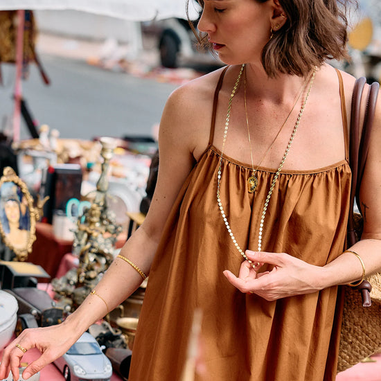 Woman in a brown dress wearing at an outdoor marketold jewellery.