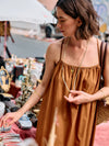 Woman in a brown dress wearing at an outdoor marketold jewellery.