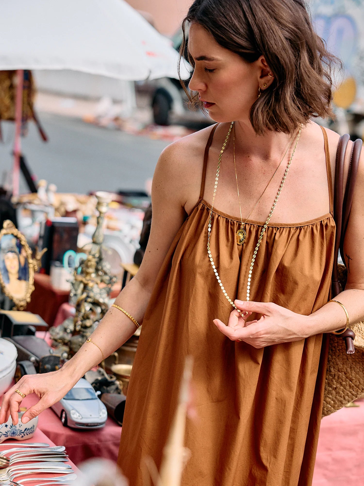 Woman in a brown dress wearing at an outdoor marketold jewellery.