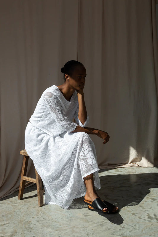 Woman in a white Beaumont organic co-ord sitting on a wooden stool against a plain background