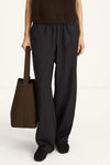Person wearing black pants holding a brown bag on a white background