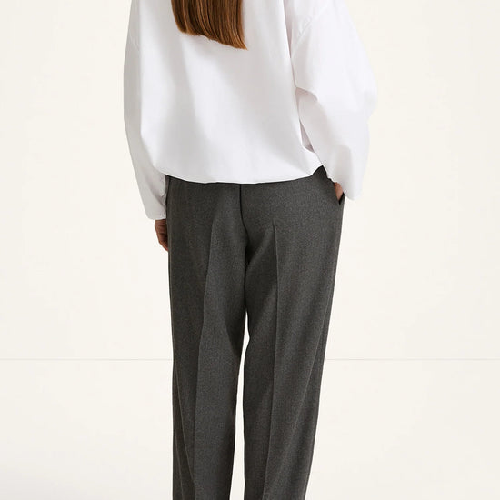 woman wearing grey trousers and white shirt rear view