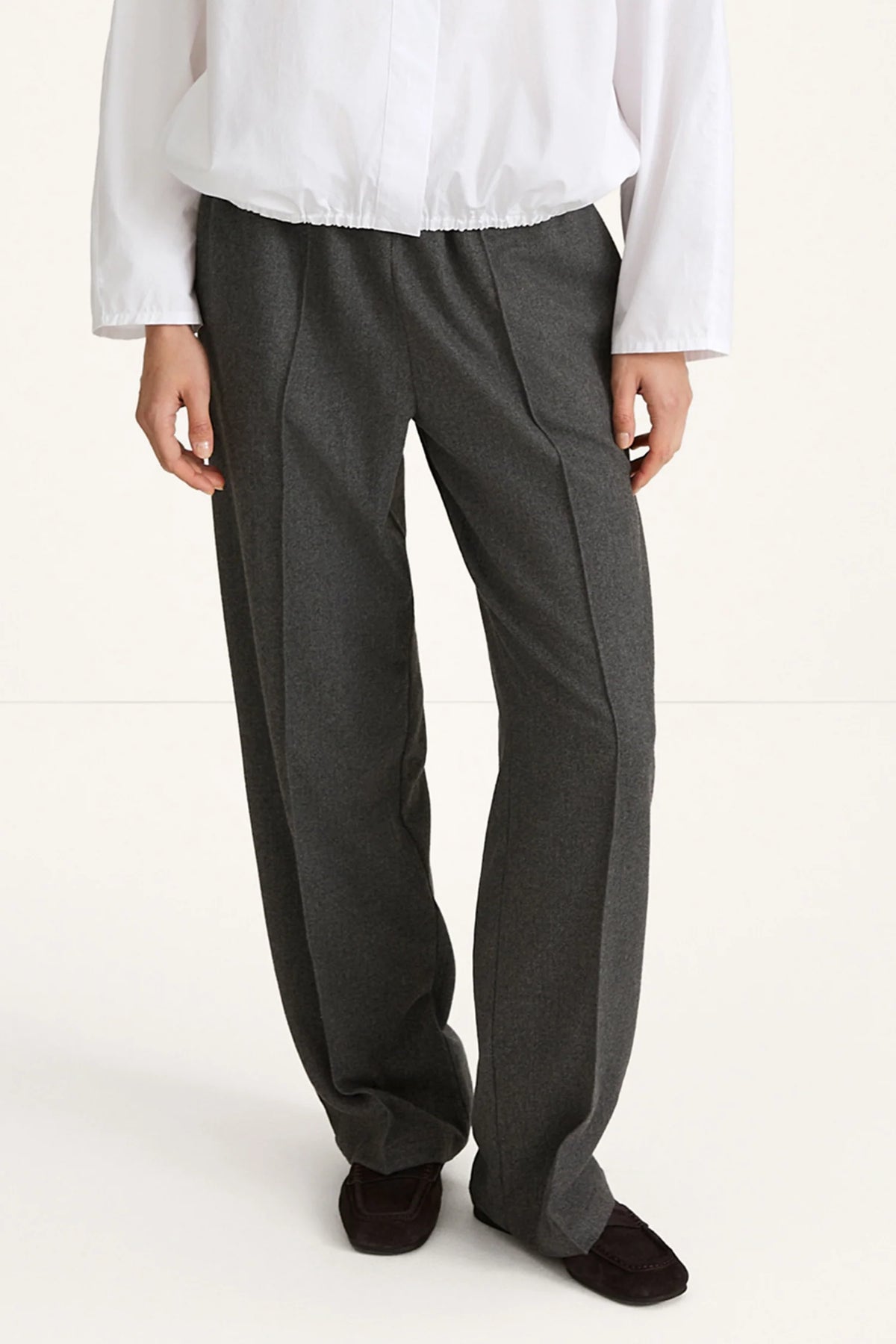 woman wearing grey trousers and white shirt rear view
