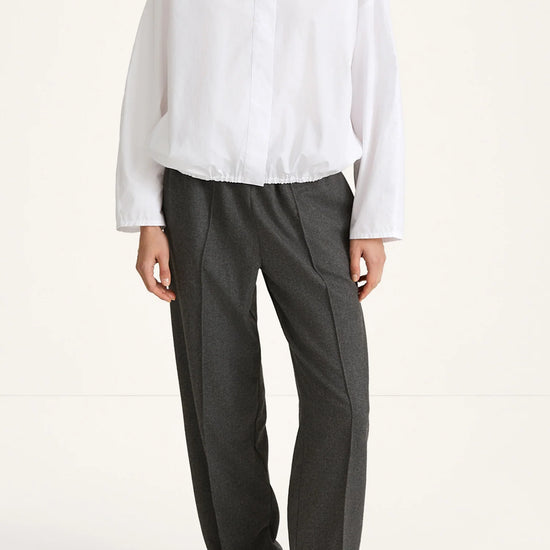 Person wearing a white blouse and gray pants on a white background