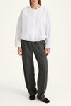 Person wearing a white blouse and gray pants on a white background
