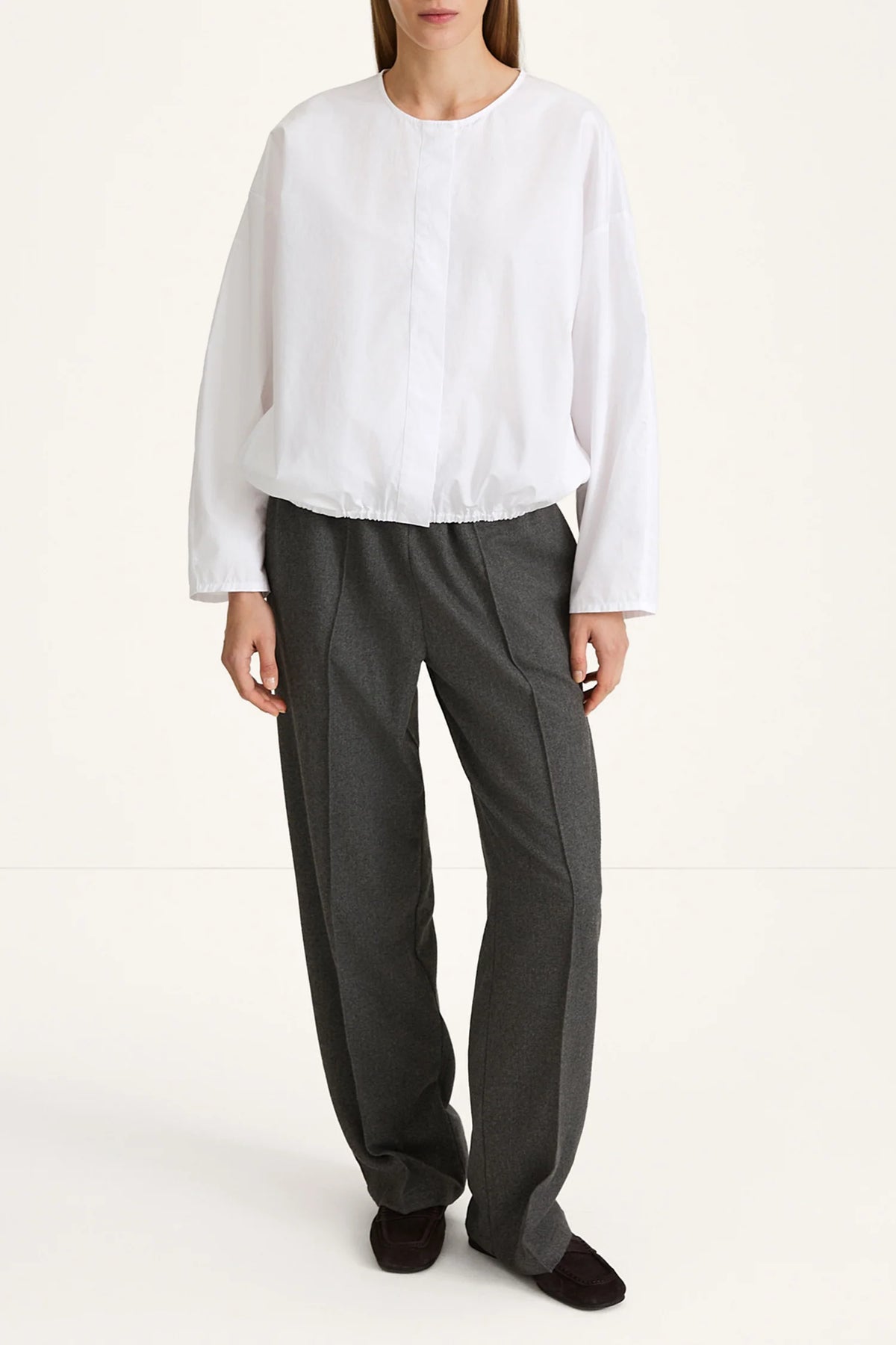 Person wearing a white blouse and gray pants on a white background