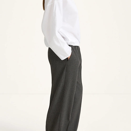 Person wearing a white shirt and gray pants on a white background