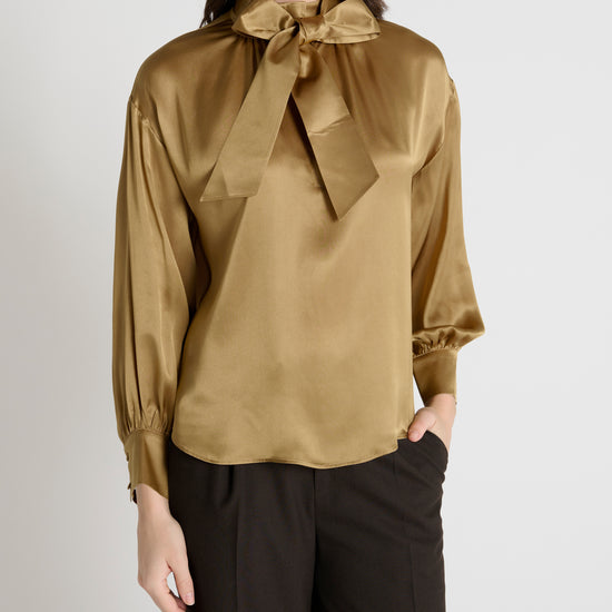 gold satin blouse with a tie bow at the neck and buttoned cuffs