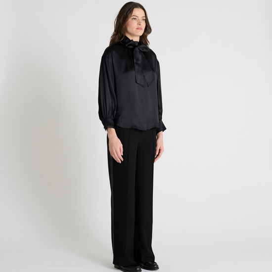 black satin blouse with a tie bow at the neck and buttoned cuffs model shot
