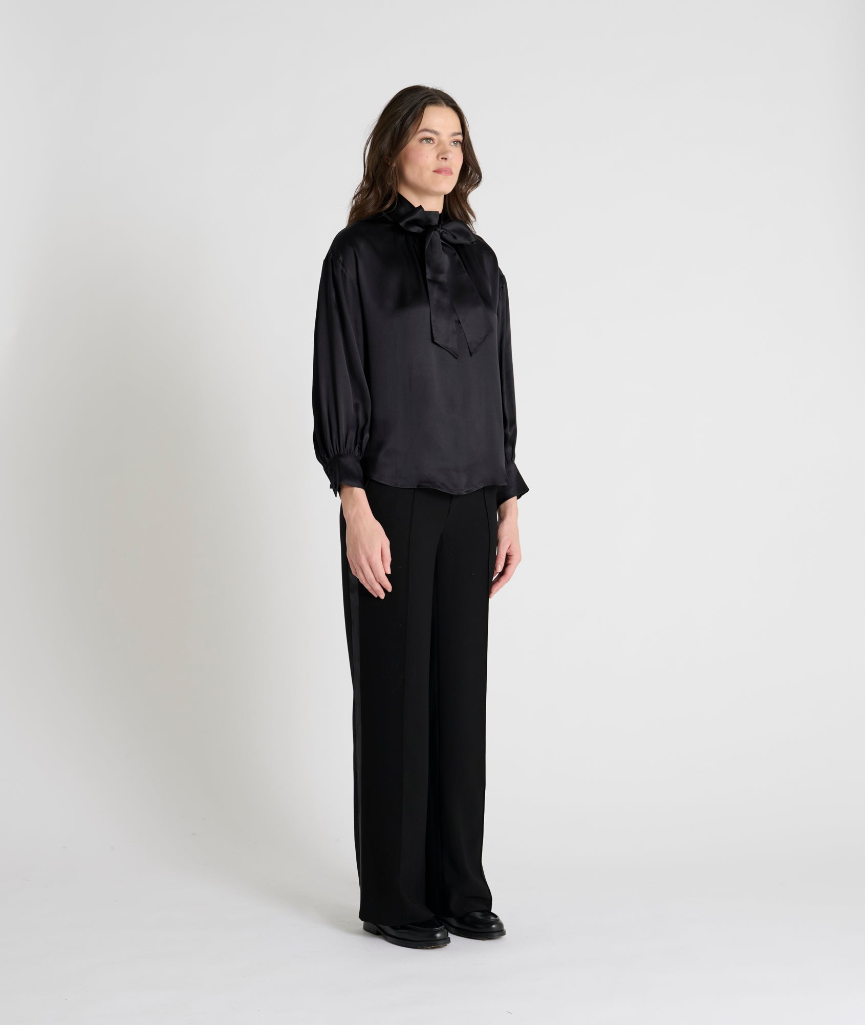 black satin blouse with a tie bow at the neck and buttoned cuffs model shot