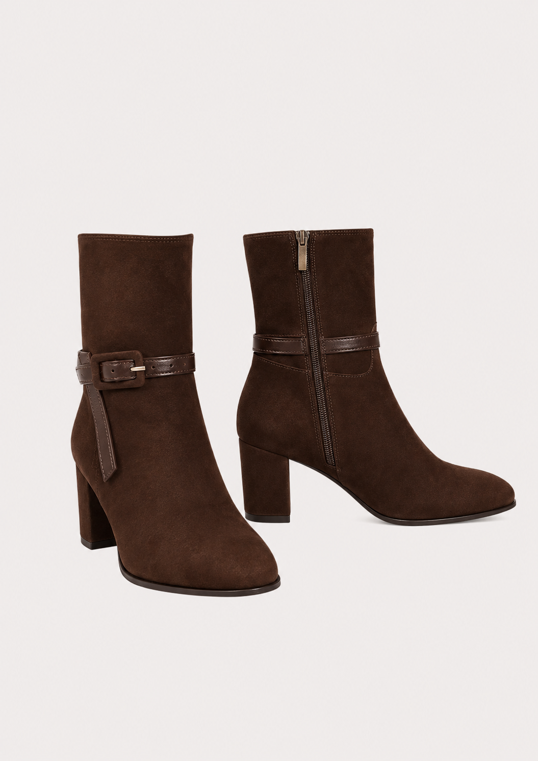 A pair of dark brown suede ankle boots with block heels and a matching faux-leather buckle strap around the ankle, shown against a plain light beige background.