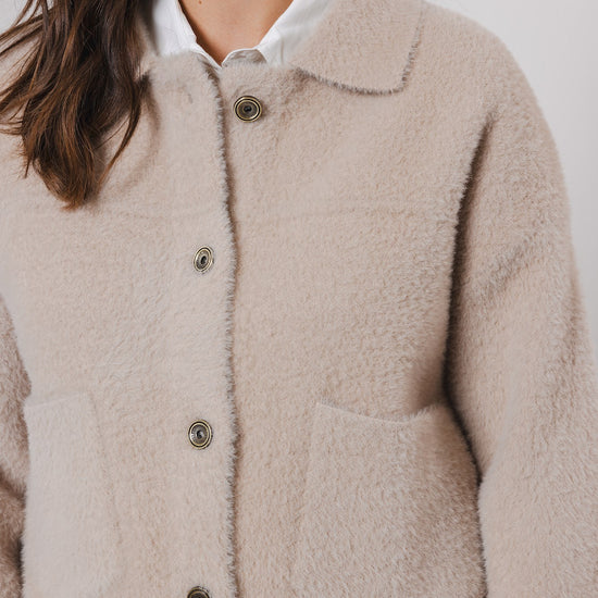 boxy beige soft cardigan with 2 front patch pockets and traditional collar close up
