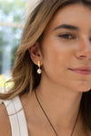 Close-up of a woman wearing a pearl earring with a blurred outdoor background