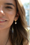 Close-up of a woman wearing a pearl earring with a blurred outdoor background