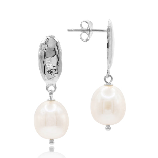 Pearl earrings by Claudia Bradby with silver hooks on a white background
