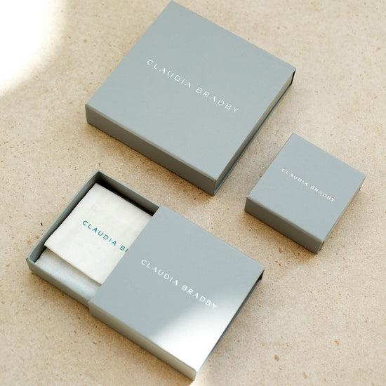 Three gray boxes with 'Claudia Bradby' branding on a beige surface
