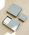 Three gray boxes with 'Claudia Bradby' branding on a beige surface