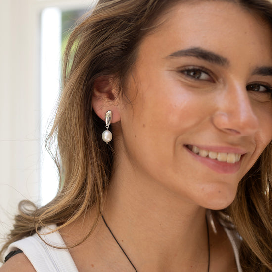 Woman wearing pearl earrings by Claudia Bradby with a blurred background