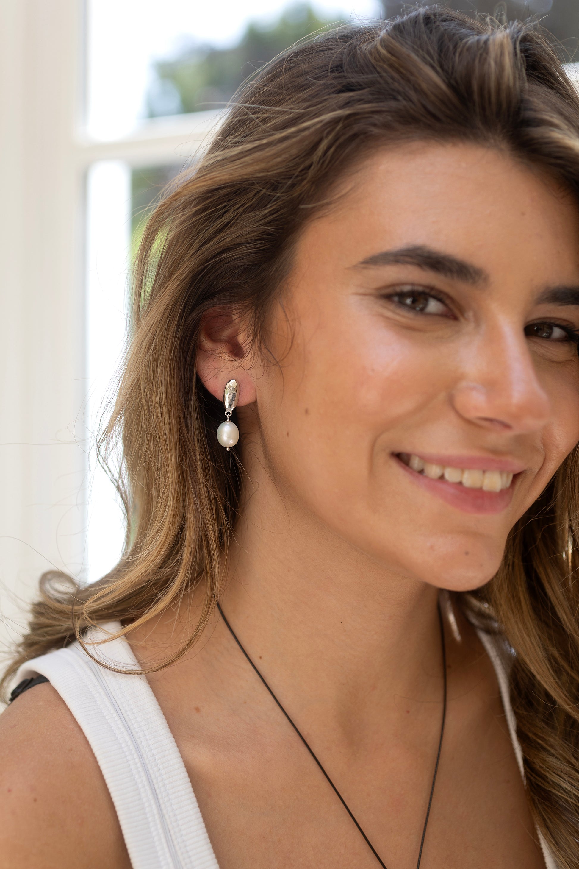 Woman wearing pearl earrings by Claudia Bradby with a blurred background