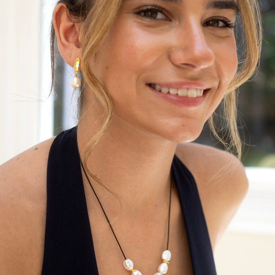Woman wearing a pearl necklace with a blurred outdoor background