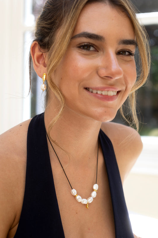 Woman wearing a pearl necklace with a blurred outdoor background
