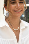 Woman wearing a pearl necklace and earrings with a blurred background
