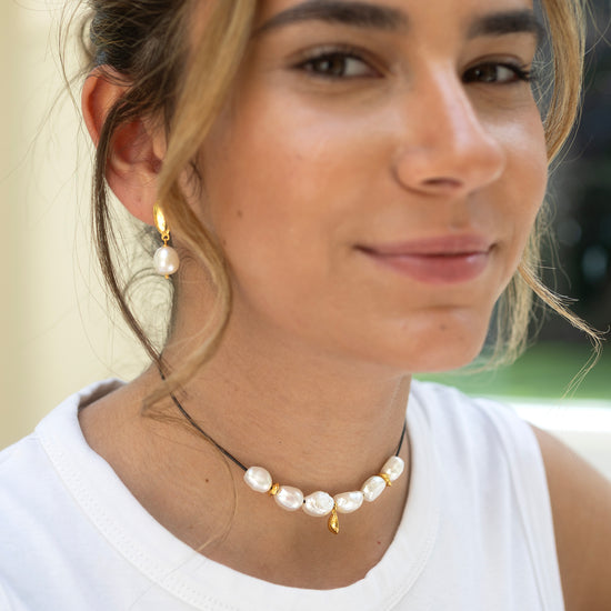 Woman wearing a pearl necklace and earrings with a blurred background