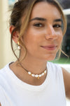Woman wearing a pearl necklace and earrings with a blurred background