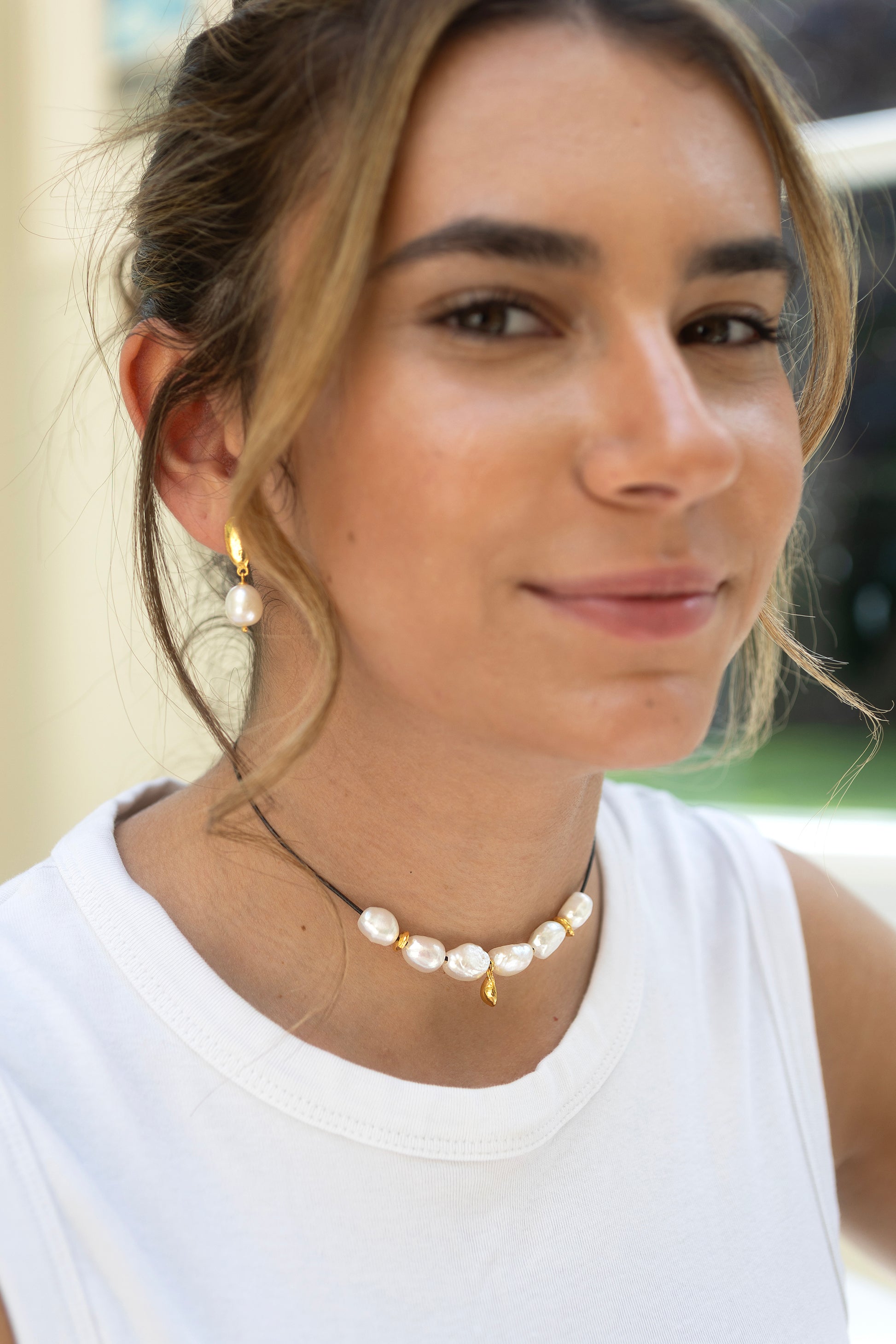 Woman wearing a pearl necklace and earrings with a blurred background