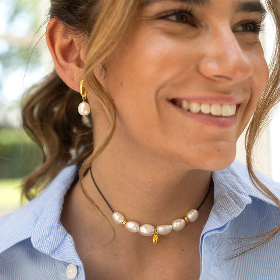 Woman wearing a pearl necklace and earrings outdoors