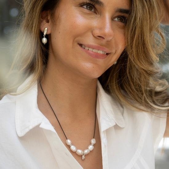 Woman wearing a white blouse and pearl necklace with blurred background
